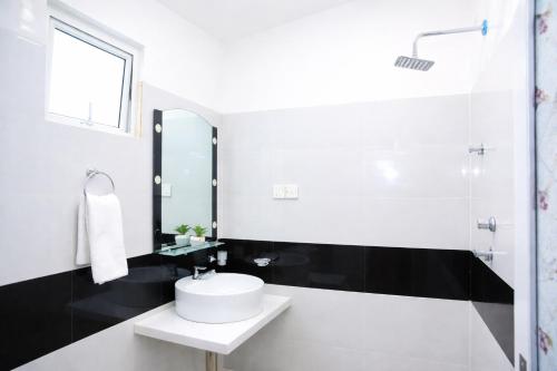 a white bathroom with a sink and a mirror at Blue Diamond Resort in Trincomalee