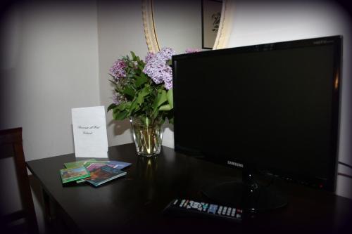 a desk with a computer monitor and a vase of flowers at Hotel Calzaiolo in San Casciano in Val di Pesa