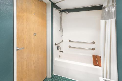 a bathroom with a white tub and a shower at Days Inn by Wyndham Neenah in Neenah