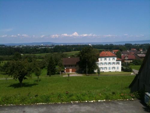 a view of a white house in a green field at Landgasthof Winzelnberg in Egnach