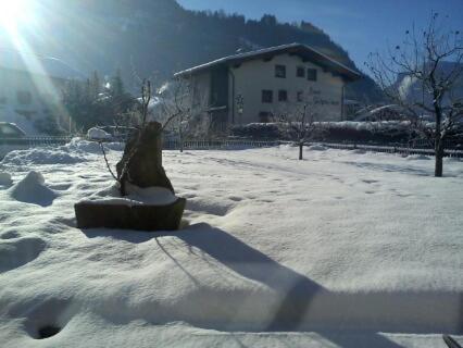 a snow covered yard with a house in the background at Hotel Garni Elisabeth in Zell am Ziller