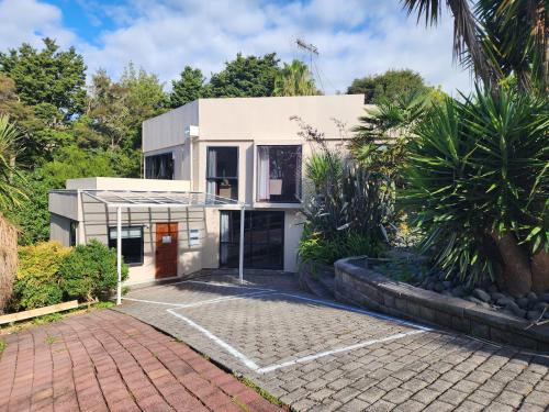 a white house with a brick driveway at Entire home in Birkenhead in Auckland