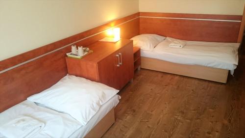 a room with two beds and a table with a lamp at Penzión Biela Voda in Veľká Lomnica