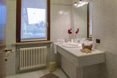un bagno con un lavandino, uno specchio e una finestra di Appartamento Ai Prati a Lazise