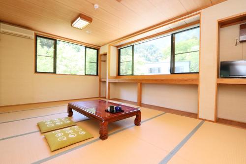 a room with a table and a tv and windows at Fukuichi in Nambu