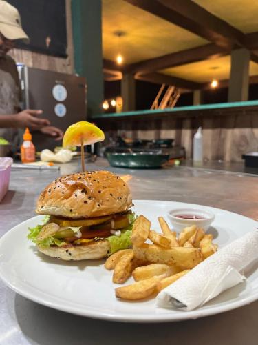 un hamburger e patatine fritte su un piatto bianco di Beach Break Surf Hostel a Weligama