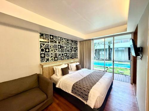a bedroom with a bed and a couch and a window at Dealton Hotel Sanur in Sanur