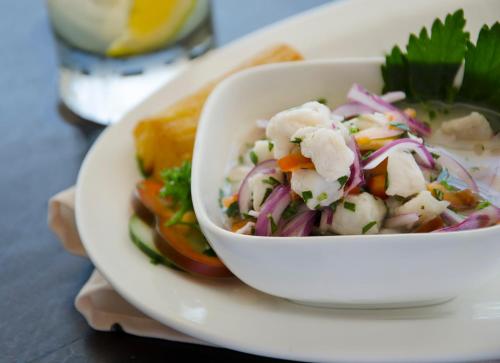 a white bowl of salad on a plate with a sandwich at Hotel Puntarenas Beach in Puntarenas