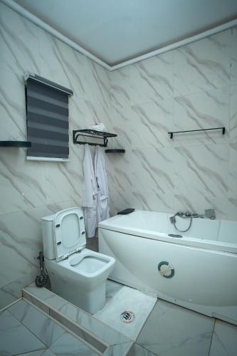 a white bathroom with a toilet and a sink at Emiez Apartment and Hotel in Benin City