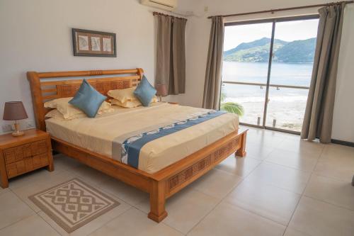 a bedroom with a bed with a view of the ocean at Surfers Cove Apartments in Bel Ombre