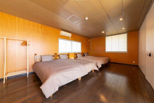 two beds in a room with wooden walls and wood floors at セト ヴィスタ 牛窓 in Setouchi