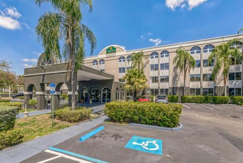 a large building with palm trees in a parking lot at La Quinta by Wyndham Miami Lakes in Miami Lakes