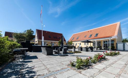a building with a courtyard with tables and flowers at Toftegården Guesthouse - Rooms in Skagen