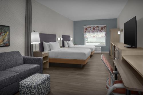 a hotel room with two beds and a couch at Home2 Suites By Hilton Concord Charlotte in Concord