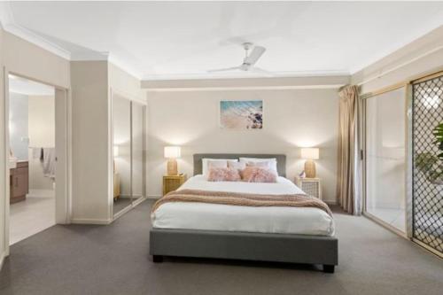a bedroom with a large bed with pink pillows at Tropical Resort with balcony overlooking pool in Westcourt