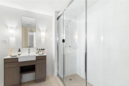 a bathroom with a shower and a sink and a mirror at Tropical Resort with balcony overlooking pool in Westcourt