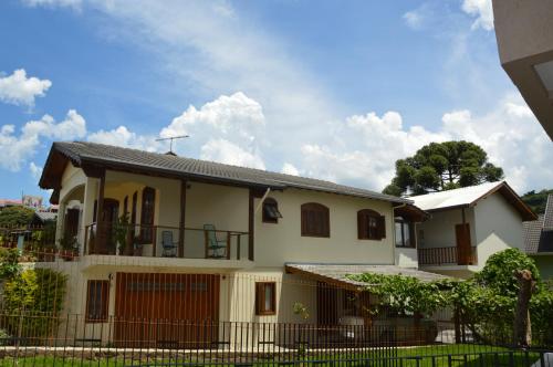 una casa blanca con una valla delante en Pousada Theisen, en Gramado