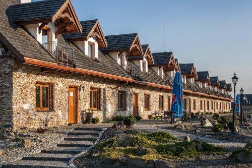 a row of stone buildings with a blue umbrella at Miłocin Park Centrum Wypoczynkowo-Konferencyjne in Pierwoszów