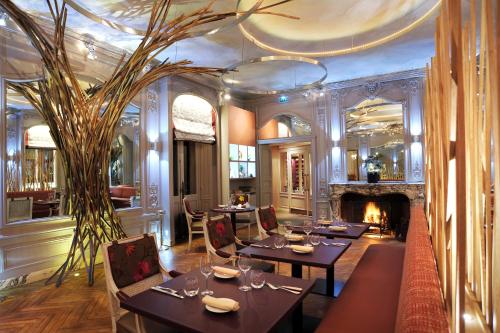 a dining room with tables and a fireplace at Hôtel L'Yeuse - Teritoria in Châteaubernard