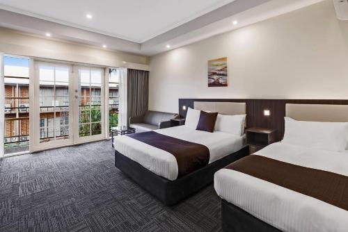 a hotel room with two beds and a couch at Quality Hotel Melbourne Airport in Melbourne