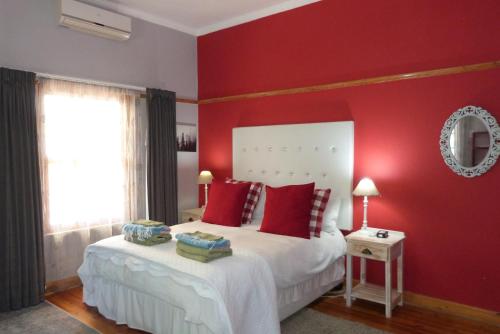 a bedroom with red walls and a bed with red pillows at Hannah's Haven in Beaufort West