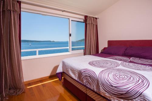 een slaapkamer met een groot raam met uitzicht op de oceaan bij Villa Vesna Private Beach in Okrug Donji