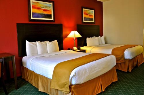two beds in a hotel room with red walls at Landmark Inn Fort Irwin in Fort Irwin