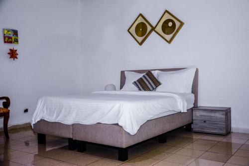 a bed with white sheets and pillows in a bedroom at PEACE GUEST HOUSE in Yaoundé
