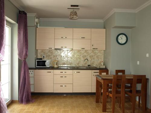 une cuisine avec des placards en bois, une table et une horloge dans l'établissement Apartament Cristal, à Szklarska Poręba