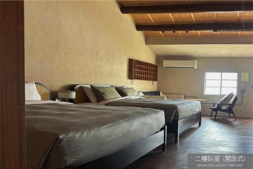 a bedroom with two beds and a chair and a window at Light Room in Tainan