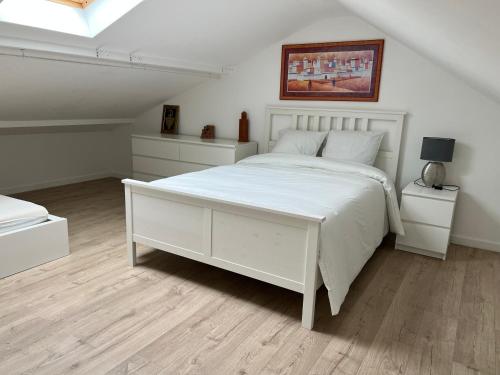 een witte slaapkamer met een wit bed en twee nachtkastjes bij Duplex 
