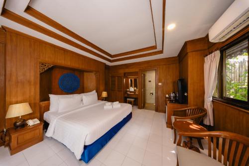 a bedroom with a large white bed and wooden walls at Sand Sea Resort Railay Beach in Railay Beach