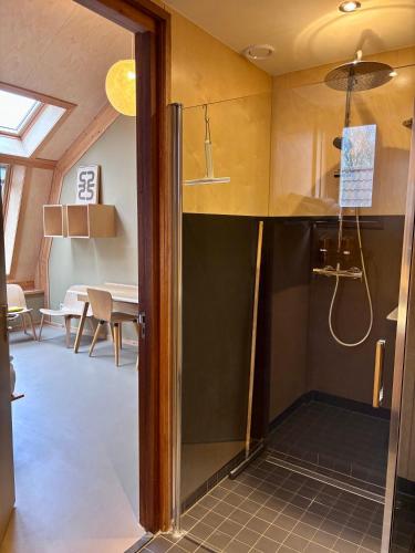 a room with a shower and a dining room at Bed & Coffee Skilleplaatsje in Den Burg