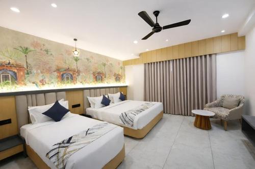 a bedroom with two beds and a ceiling fan at White Panda hotels Shree Radhe in Dwarka