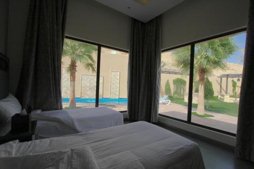 a bedroom with two beds and a large window at Marbella Resort in Al ‘Ammārīyah