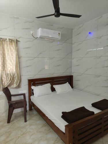 a bedroom with a bed and a chair in it at Eshwaraa Cottage in Palni