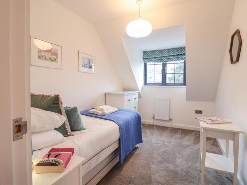 a small bedroom with a bed and a window at Corner Cottage, Thorpeness in Thorpeness
