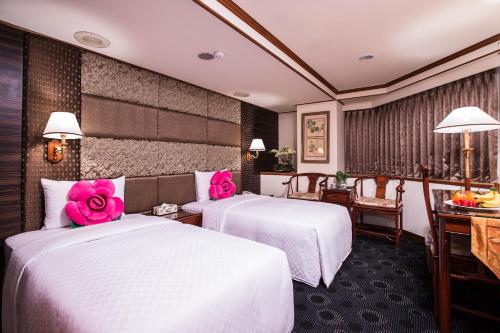 two beds in a hotel room with pink roses on them at Han She Hotel in Taipei