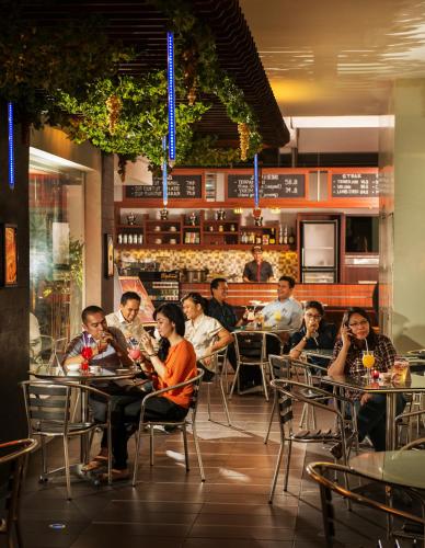 a group of people sitting at tables in a restaurant at Blue Sky Pandurata Hotel Cikini in Jakarta