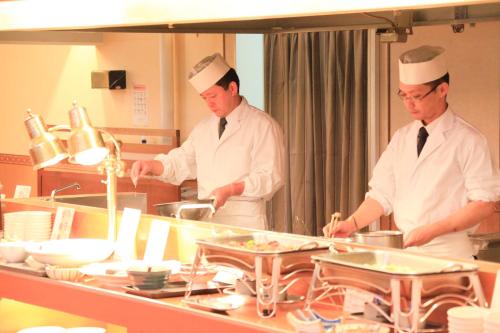 three chefs standing in a kitchen preparing food at Park Hotel Miyabitei in Noboribetsu
