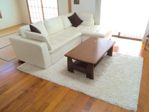 a living room with a white couch and a coffee table at Okinawa Pension Minami in Nanjo