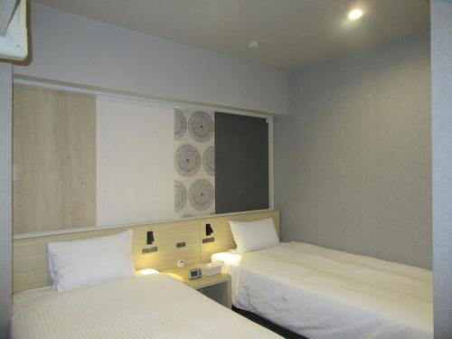 a hotel room with two beds and a window at Smile Hotel Hachinohe in Hachinohe
