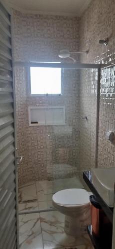 a bathroom with a toilet and a sink and a window at Rancho Duarte in Itanhaém