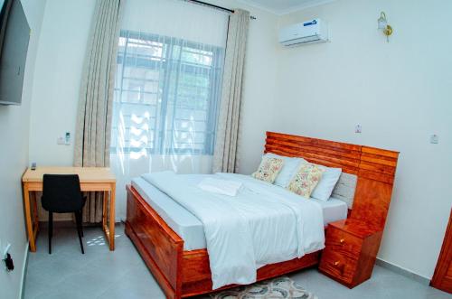 a bedroom with a bed and a desk and a window at Kibs Apartments in Dodoma