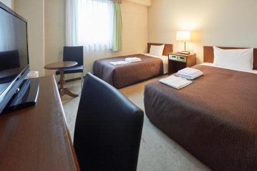 a hotel room with two beds and a desk at Select Inn Mishima in Mishima