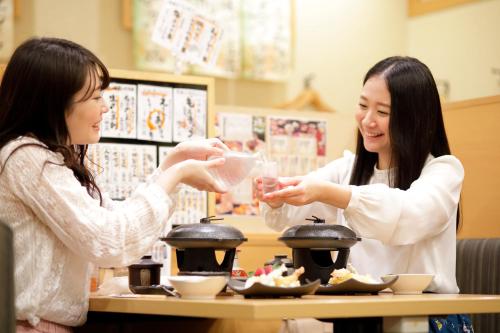 two women sitting at a table eating food at Pioland Hotel in Saitama