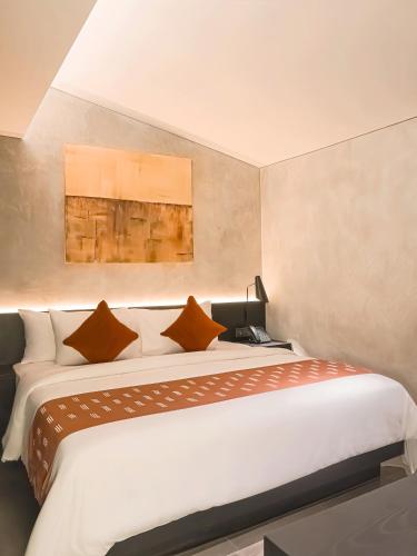 a bedroom with a large white bed with pillows at Maisola by ARTOTEL Semarang in Semarang