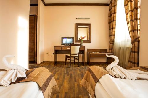 a hotel room with two beds and a desk at Family Hotel Teteven in Teteven