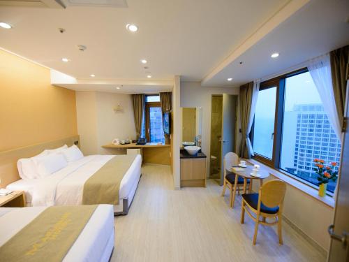a hotel room with two beds and a table and chairs at Haeundae Marianne Hotel in Busan