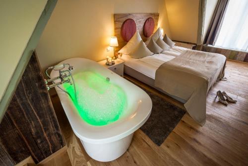 a bathroom with a bath tub and a bed at Hotel Wellness Goldenes Fass Meißen in Meißen